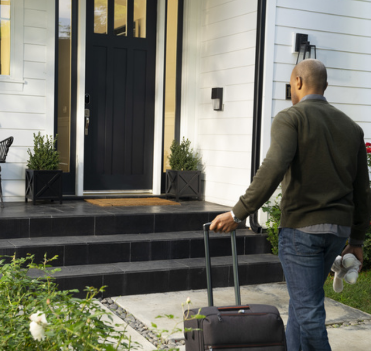Man coming home from vacation and walking towards front door using Yale Smart Lock Keypad and Yale Lever lock pair